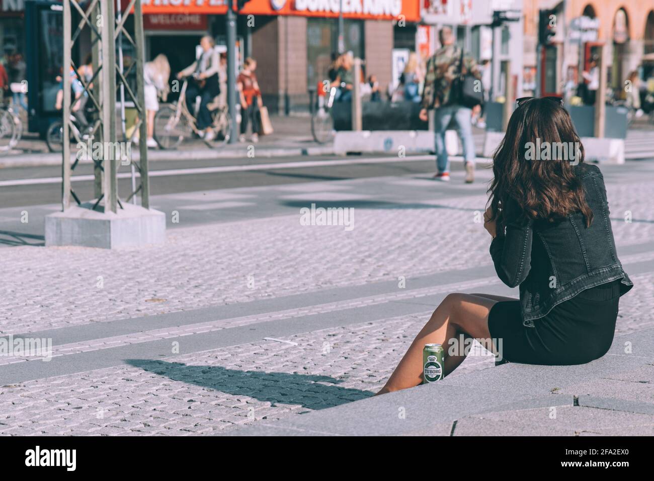 Copenhagen, Denmark - September 14, 2019. A woman drinking Green Tuborg on a sidewalk of Copenhagen`s downtown next to Burger King. Stock Photo